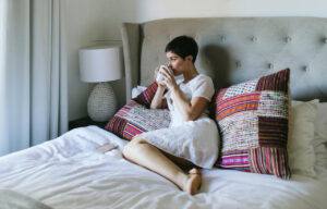Sleep-Friendly Bedroom - a woman drinking the cup of tea.
